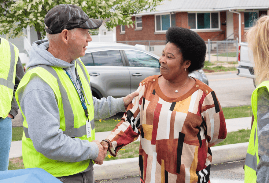 Community volunteer greeting a resident with a handshake during a local neighborhood improvement effort