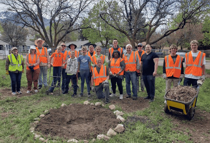 Community volunteers gathered with tools and a wheelbarrow after working on an outdoor improvement project