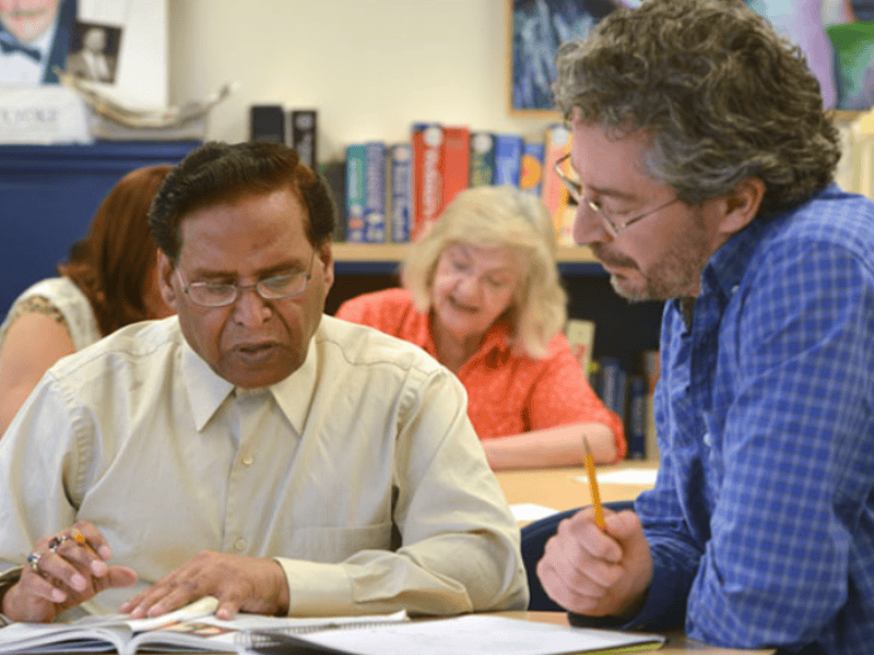 Community volunteer tutoring an adult in a learning center, promoting education, job readiness, and upward mobility through local programs in Utah