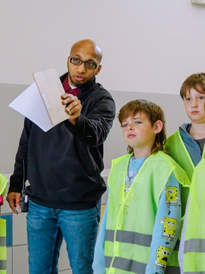 Community volunteer guiding students during an educational program, promoting youth development and upward mobility through local learning initiatives in Utah