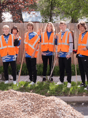 Group of youth volunteers in safety vests holding tools during a community service project, highlighting teamwork and civic engagement