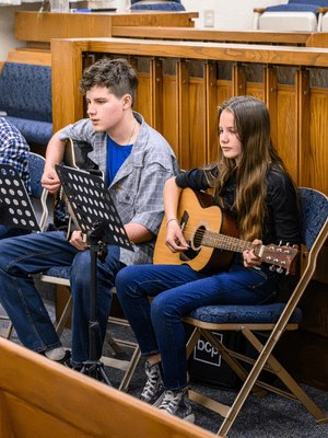 Student playing guitars at event, representing youth education, arts access, and skill development