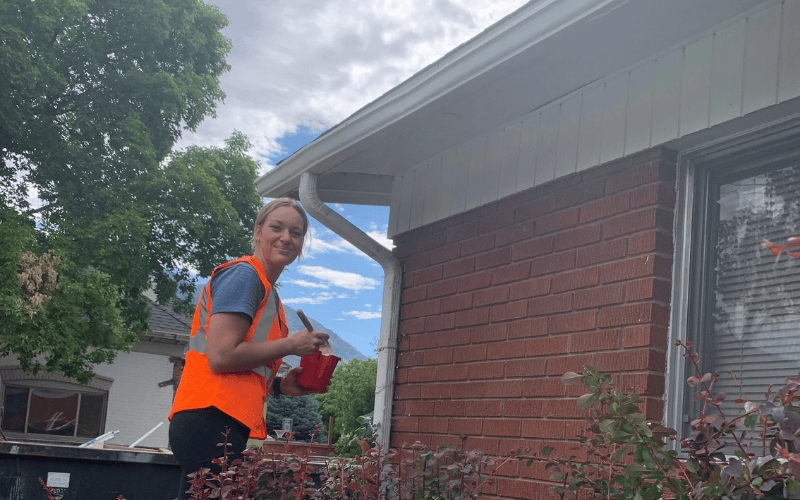Community volunteer working on home improvement during a Utah service project, promoting neighborhood revitalization and volunteer opportunities